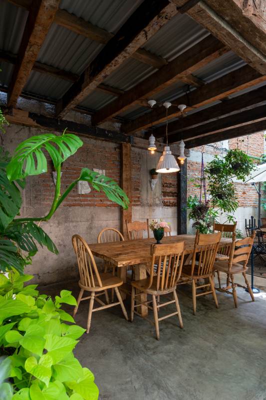 Mesa larga de madera bajo vigas, entre plantas