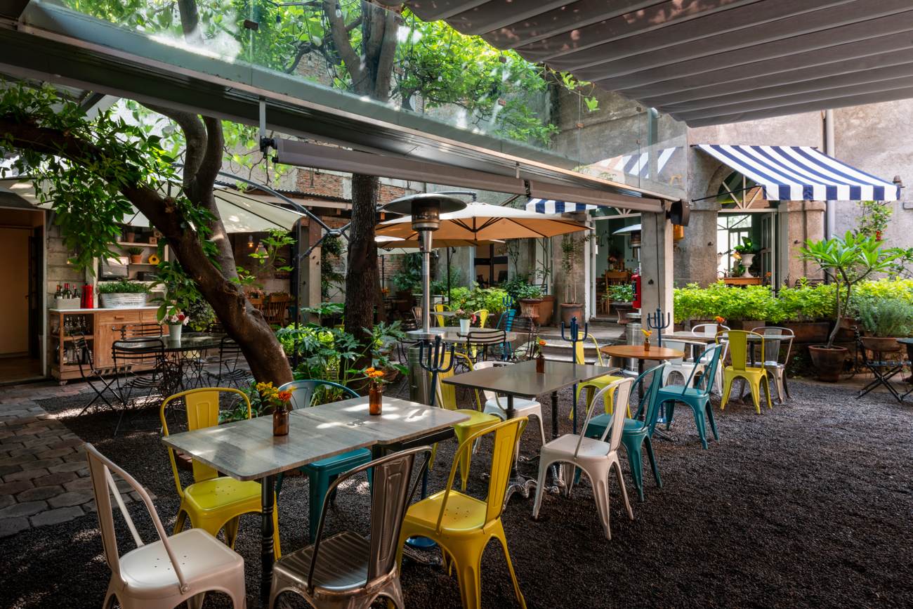 Terraza con árbol, sillas de colores y toldo de rayas